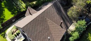 Inspector examining roof shingles and flashing beside a ladder at a residential home