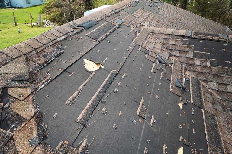 Homeowner reviews roof warranty papers beside inspection photos and roofing materials.